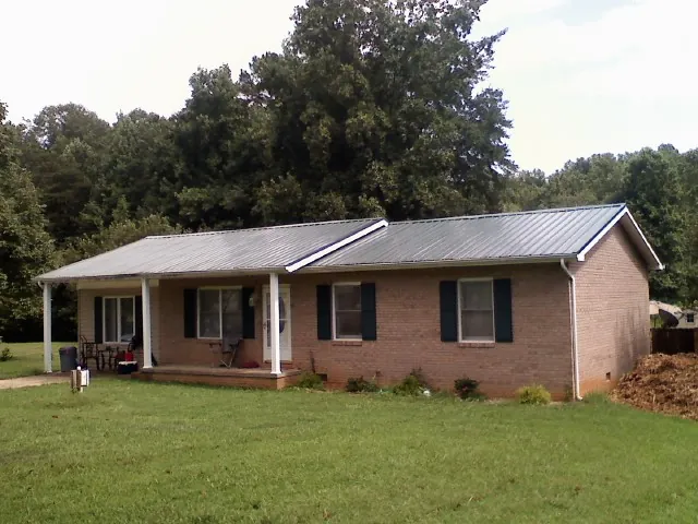 Gray metal roof on a brick ranch house with a side carport in Bagley