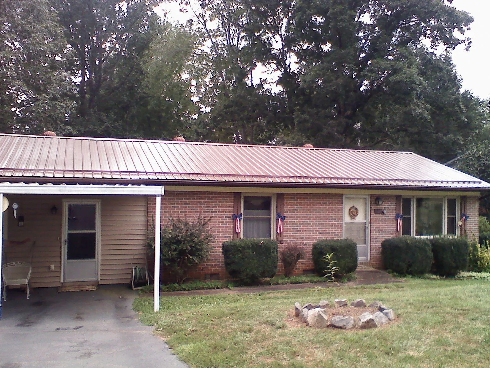 Bronze metal roof and carport on a brick ranch home — Roof Repair work by our crew in Bagley